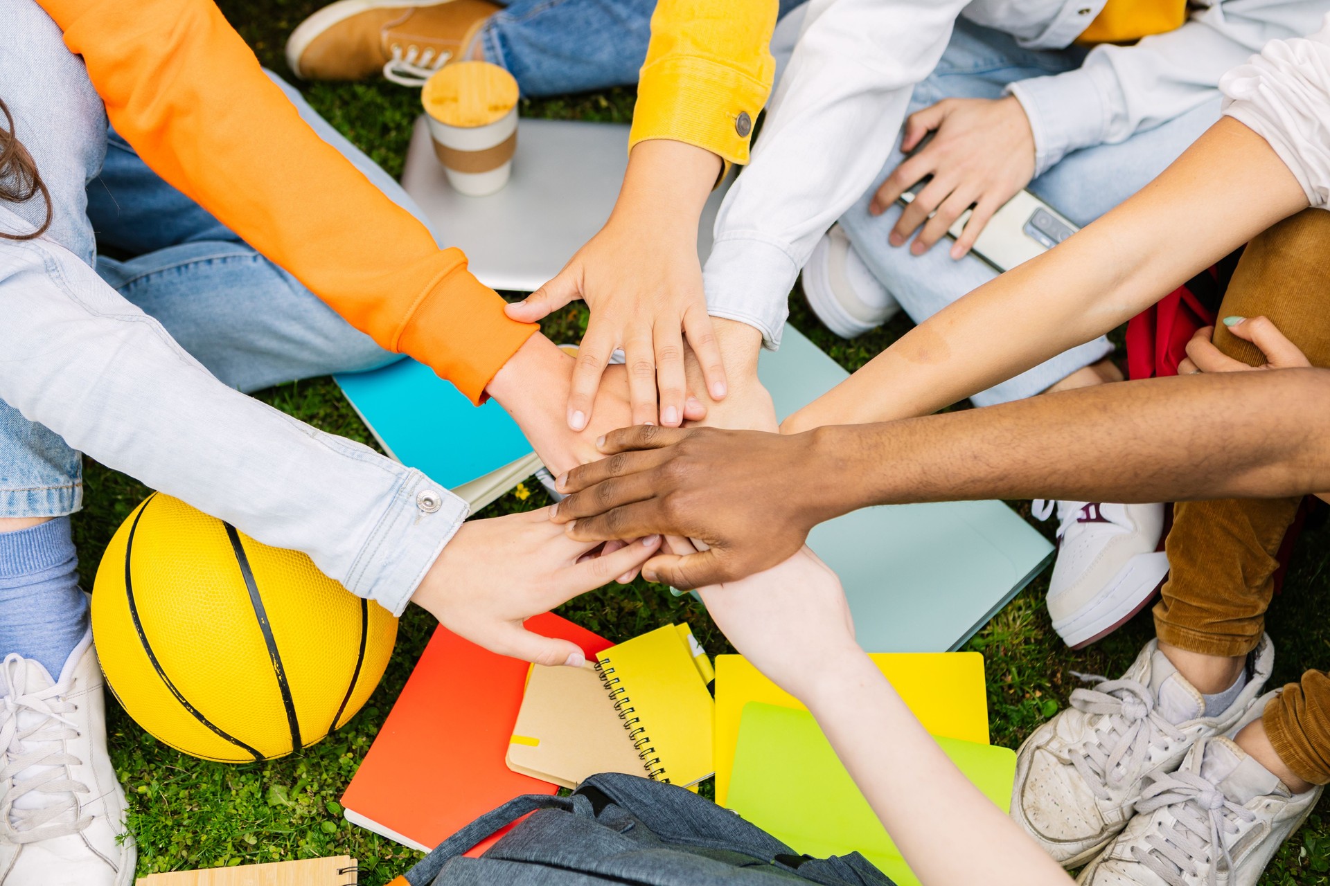 Diverse student people stacking hands together sitting at college campus